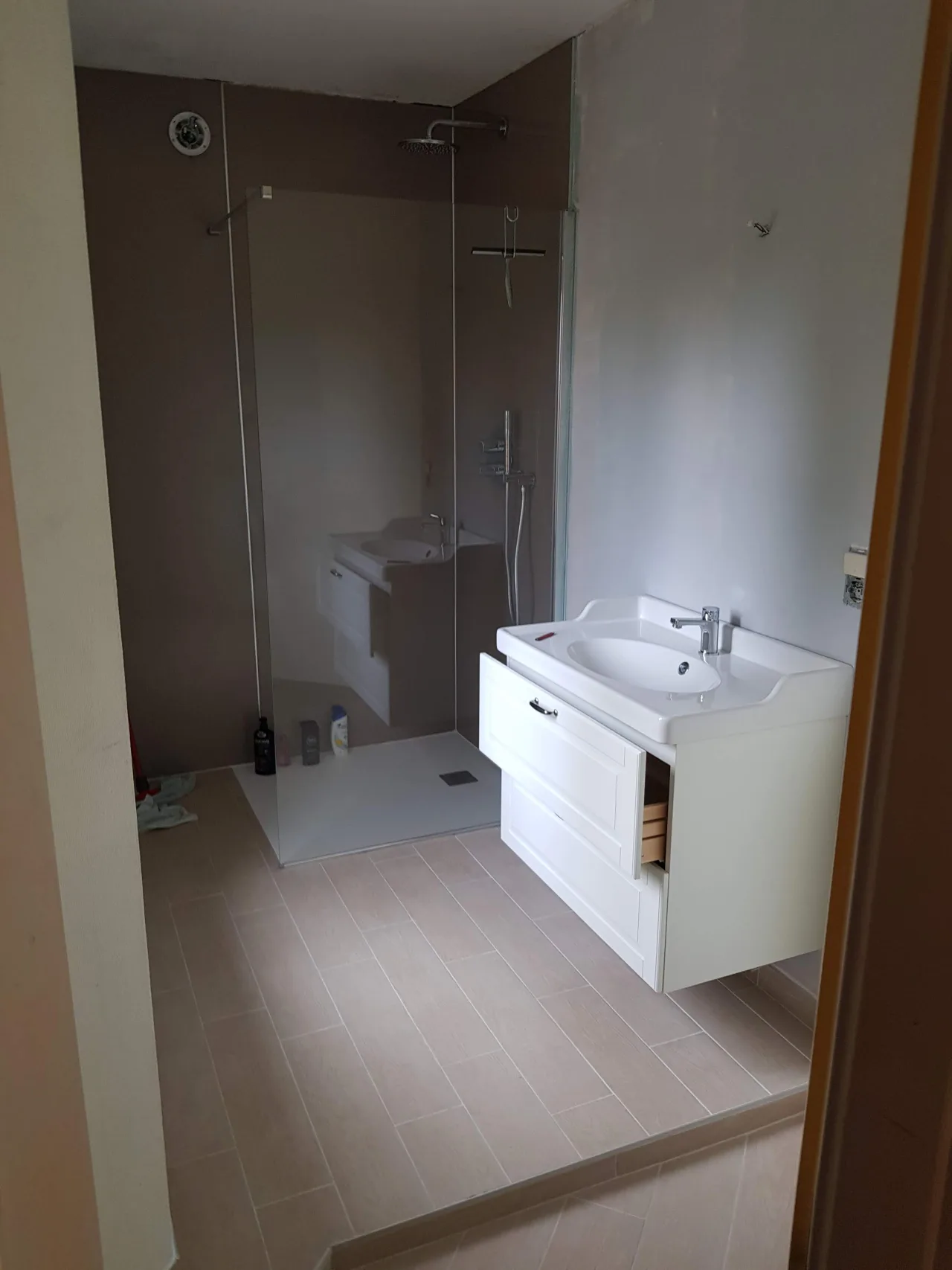 Salle de bains avec douche vitrée et meuble vasque installés sur un chantier Eston Group