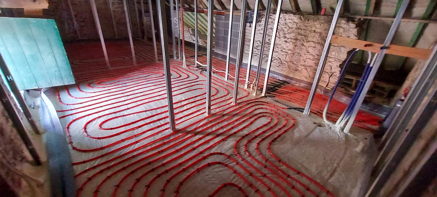 Circuits rouges d’un chauffage par le sol posés dans une pièce en travaux