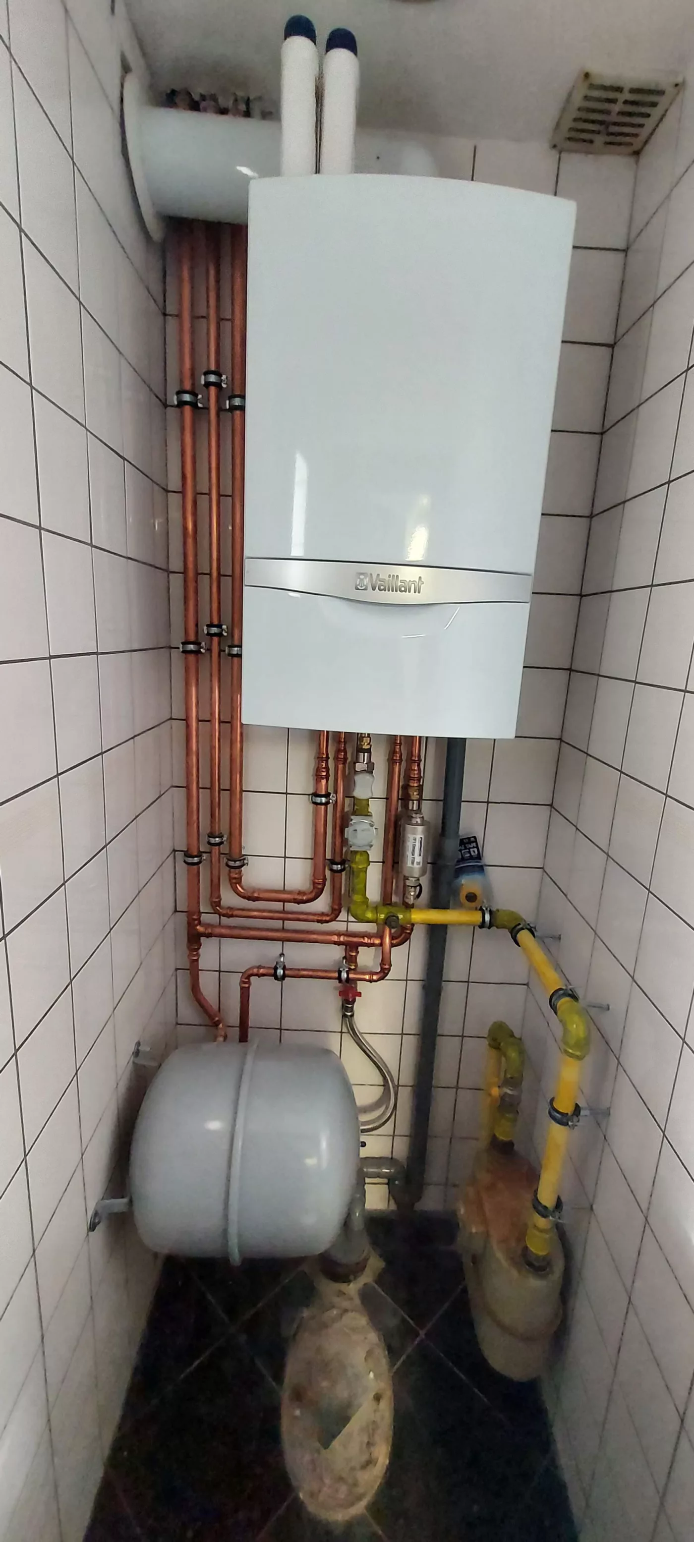 Chaudière gaz murale Vaillant et raccordements en cuivre dans un local carrelé