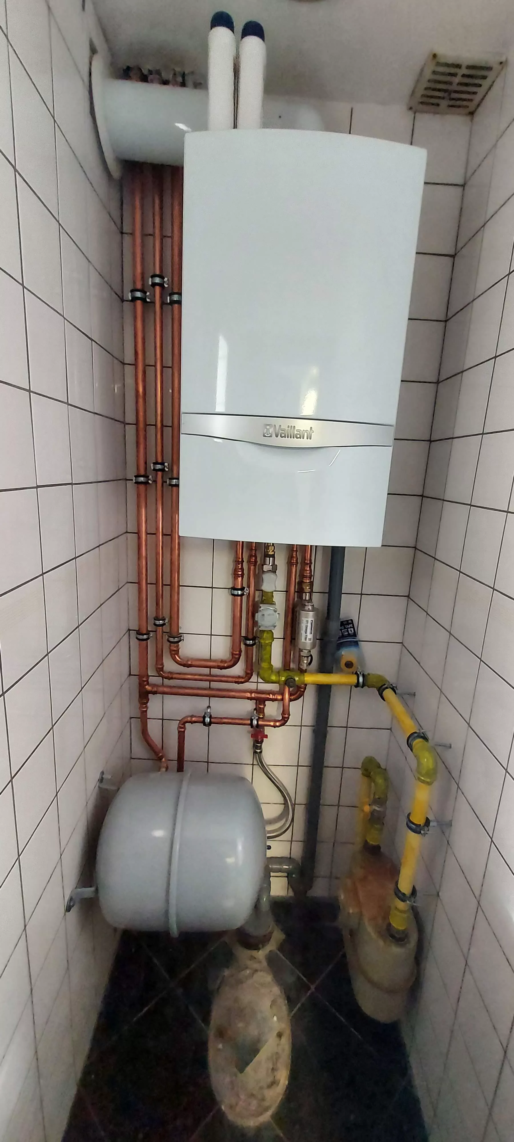 Chaudière gaz murale Vaillant et raccordements en cuivre dans un local carrelé